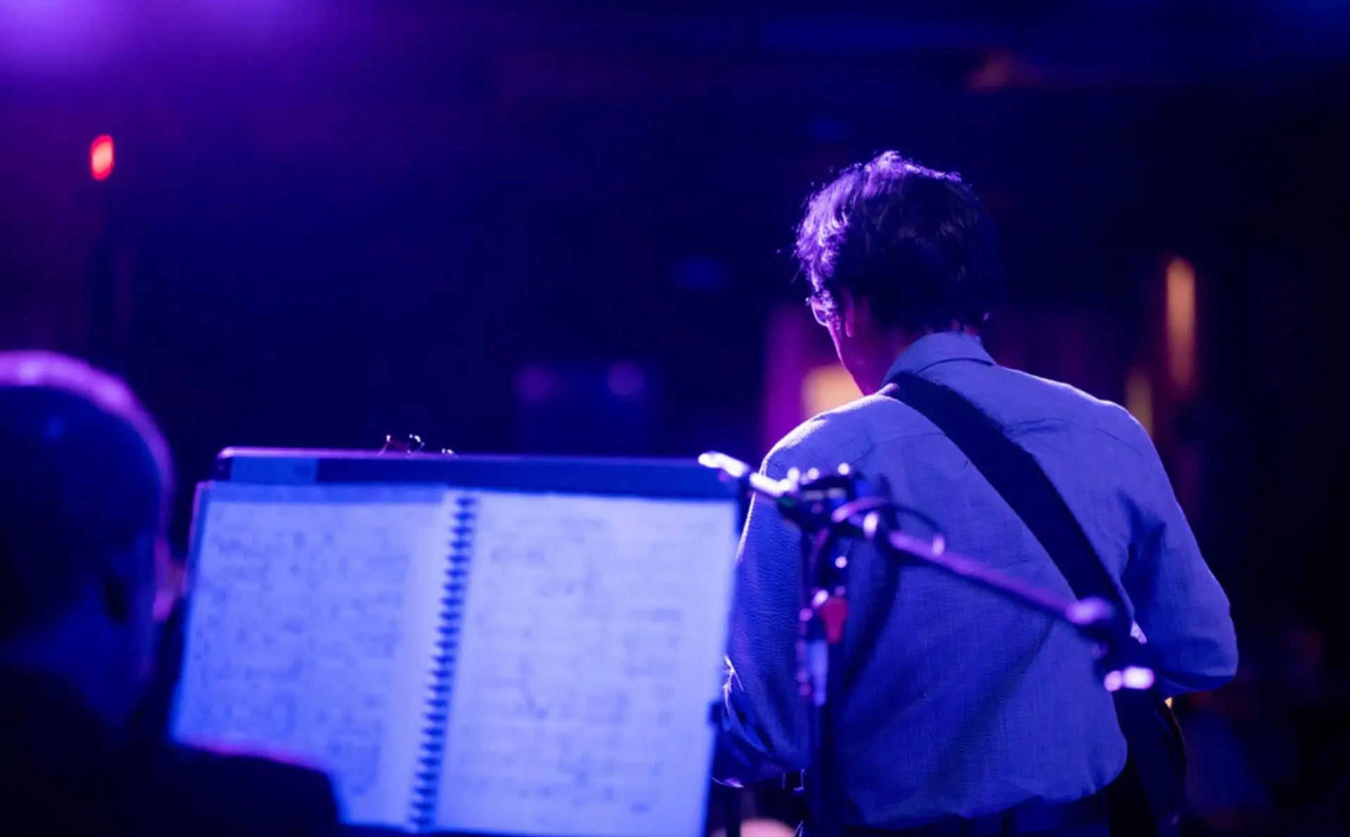 Resty Garcia reading charts on stage with his guitar during a live show with fellow musicians