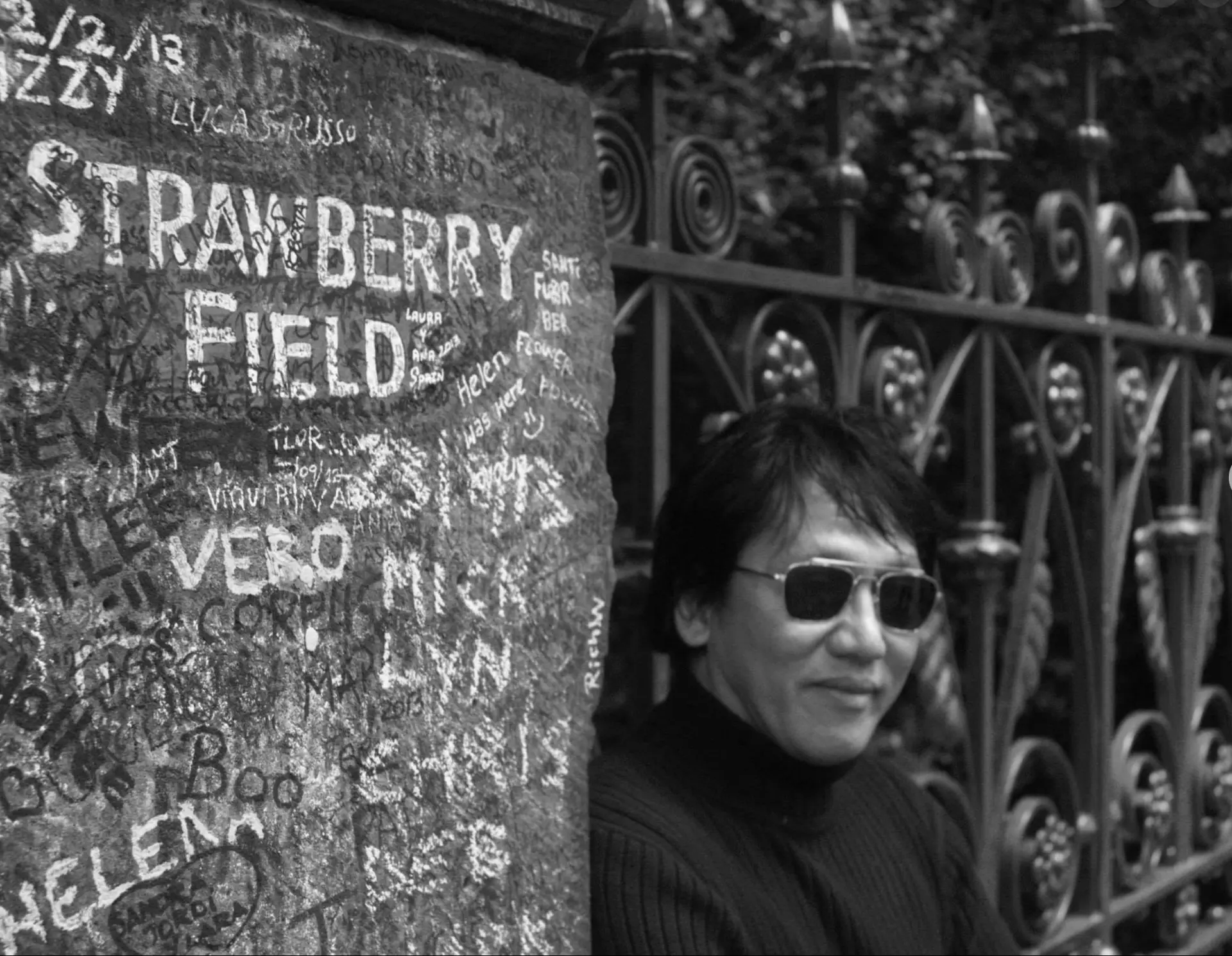 Portrait of Resty Garcia at the Strawberry Field gates in Liverpool